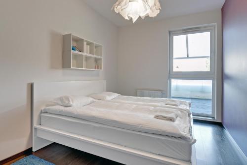 a white bedroom with a bed and a window at Downtown Apartments Hallera 165 in Gdańsk