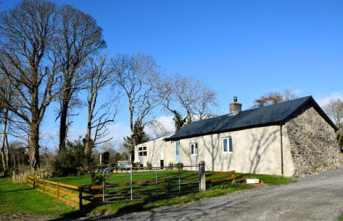 a white barn with a black roof on a road at Tuck Mill Cottage in Castlewellan
