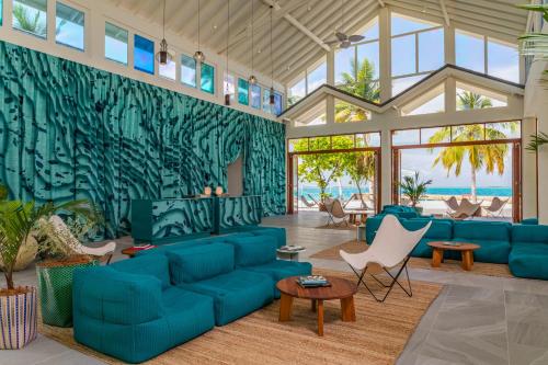 ラア環礁にあるThe Standard, Huruvalhi Maldivesの青いソファと椅子付きの広いリビングルーム