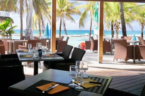 a restaurant with tables and chairs and the beach at MANGANAO LOFTS INN Bord de Mer in Saint-François