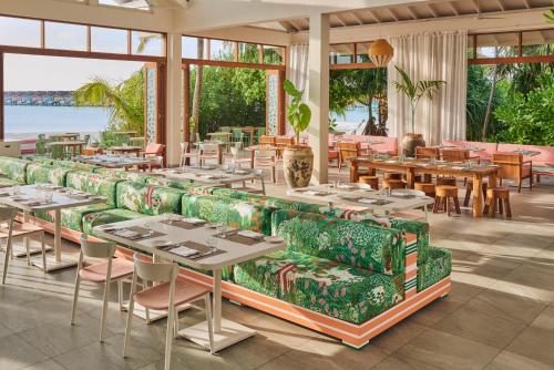um restaurante com sofás verdes, mesas e janelas em The Standard, Huruvalhi Maldives em Raa Atoll