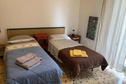 a bedroom with two beds and a table and a window at A casa da Claudio in Parma