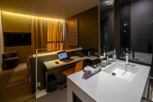 a bathroom with a sink and a desk with a laptop at Noom Hotel Niamey in Niamey