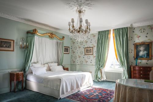 - une chambre avec un lit et un lustre dans l'établissement Château D'Apigné Rennes, à Le Rheu