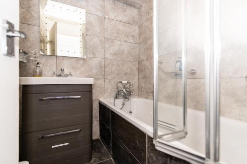 a bathroom with a tub and a sink and a shower at Bray Guest Rooms in London