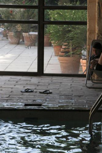 une personne assise dans une chaise à côté d'une piscine dans l'établissement Ancienne Abbaye de Franquevaux Lou Pitchoun, à Franquevaux