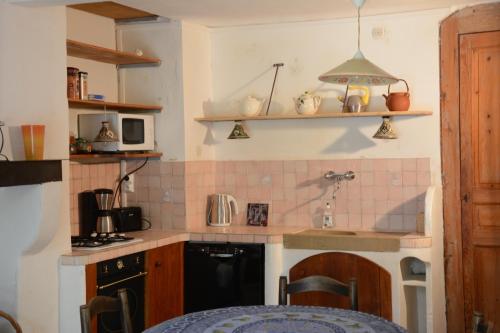 une petite cuisine avec un évier et une cuisinière dans l'établissement Ancienne Abbaye de Franquevaux Lou Pitchoun, à Franquevaux