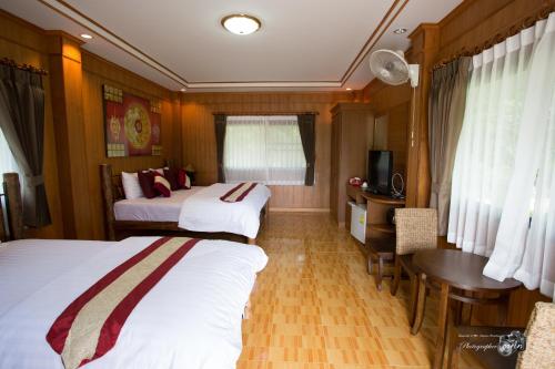 a bedroom with two beds and a desk and a table at Papai Country Lodge SHA in Ban Mae Pong