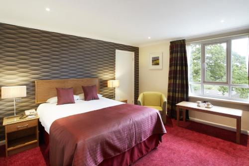 a hotel room with a large bed and a window at The Manor House At Celtic Manor in Newport