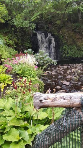 a garden with a waterfall and a log at Captain's Rest with Hot Tub and Sauna in Dunvegan