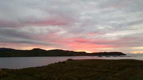 a sunset over a body of water with mountains at Captain's Rest with Hot Tub and Sauna in Dunvegan