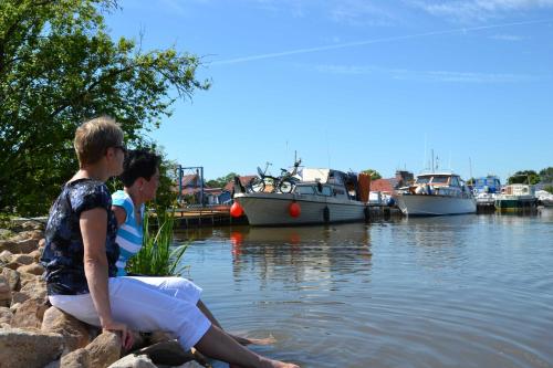 deux garçons assis sur des rochers près de l'eau avec des bateaux dans l'établissement Ferienwohnung Kapitänshus, 25668, à Weener