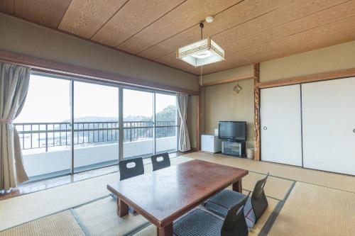a living room with a table and a large window at Tabist Miyoshi Ryokan Odawara Manazuru in Odawara