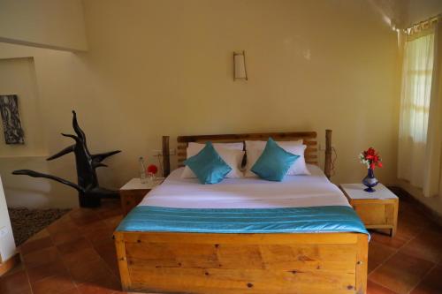 a bedroom with a wooden bed with blue pillows at Pranavam Resort & Spa in Tariyod