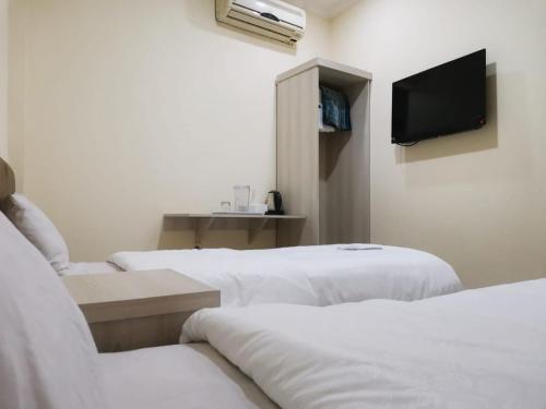 a room with two beds and a tv on the wall at Hotel Nusantara Indah Syariah in Jakarta