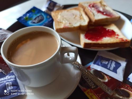 a cup of coffee and a plate of bread at TGF Dream Guest House in Majorda