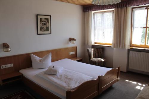 Schlafzimmer mit einem Bett, einem Stuhl und Fenstern in der Unterkunft Waldgasthof - Hotel Schiederhof in Wiesenfelden