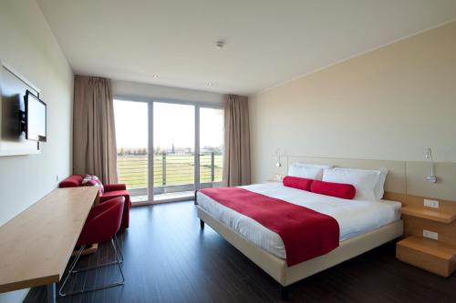ヴィッロルバにあるUNAHOTELS Le Terrazze Treviso Hotel & Residenceのベッドと大きな窓が備わるホテルルームです。