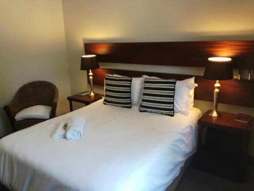 a hotel room with a large white bed with pillows at Belmont Guesthouse in Bloemfontein
