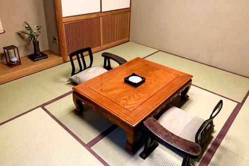 a wooden table and chairs in a room at Tabist Kappo-Ryokan Ooriya Kochi in Sagamichō
