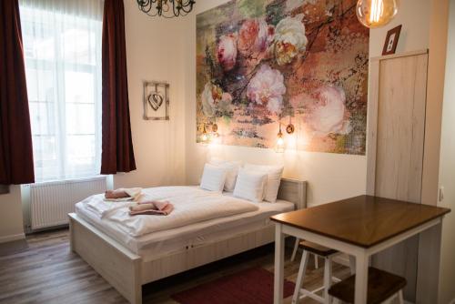 a bedroom with a bed and a table and a painting at All In Apartman IV. in Budapest