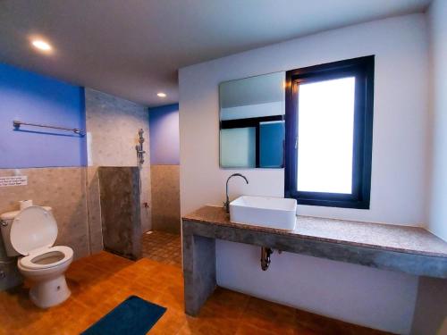 a bathroom with a toilet and a sink and a window at 2 Home in Chalong 