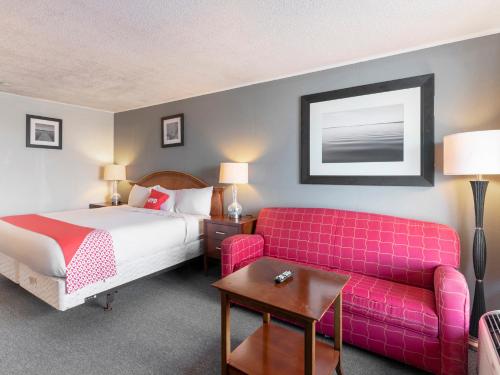 um quarto de hotel com uma cama e um sofá rosa em OYO Hotel Jennings I-10 em Jennings