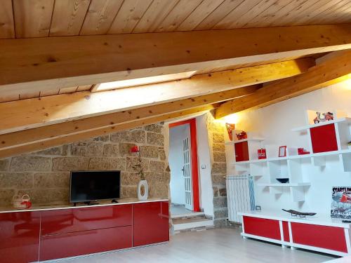 a living room with a tv and a stone wall at Al Vecchio Corso B&B in Tempio Pausania
