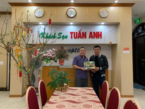 deux hommes debout devant une pièce avec une table dans l'établissement Tuan Anh Cua Lo Hotel, à Cửa Lô