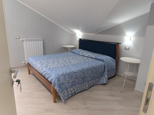 1 dormitorio con 1 cama con edredón azul y 2 mesas en DADA, en Giffoni Valle Piana