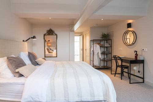a bedroom with a large white bed and a desk at Empire suites roof terras in Amsterdam