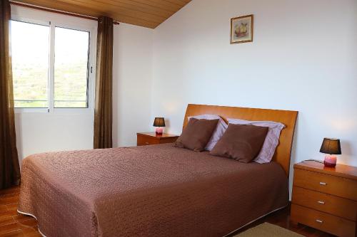 1 dormitorio con 1 cama con 2 mesitas de noche y una ventana en Casa Bela Vista, en Ribeira Brava