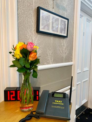 a vase of flowers sitting on a table with a phone at Northumberland Hotel in Edinburgh
