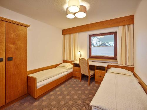 a room with two beds and a desk and a window at Apparthof Sunnwies in Oetz