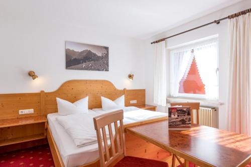 a bedroom with two beds and a wooden table at Landhaus Almrausch in Mittelberg