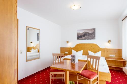 a hotel room with a bed and a table and chairs at Landhaus Almrausch in Mittelberg