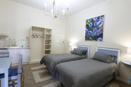 a bedroom with two beds and a kitchen at Green Olive Guesthouse in Robertson