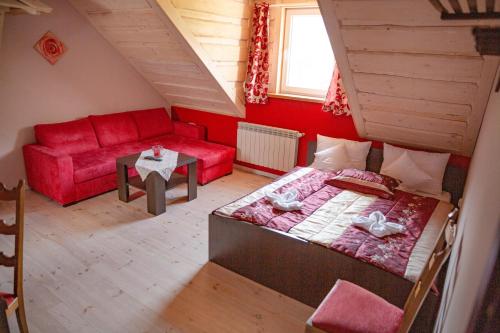 a living room with a red couch and a bed at Willa i domki Victoria in Wisła