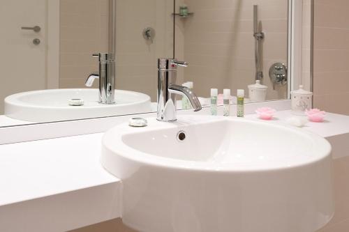bagno bianco con lavandino e specchio di UNAHOTELS Le Terrazze Treviso Hotel & Residence a Villorba