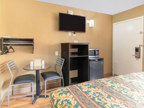 Habitación de hotel con cama, mesa y TV. en OYO Hotel Lake Charles Hwy 10, en Lake Charles