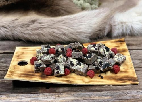 a wooden cutting board topped with chocolate and raspberries at Levi Black Apartments in Levi