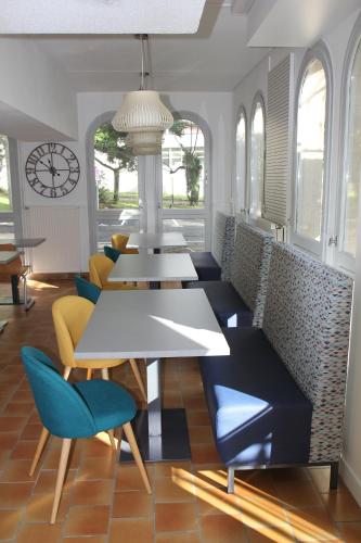 a dining room with tables and chairs and a clock at AUBERGE DE JEUNESSE D'ORLEANS in Orléans