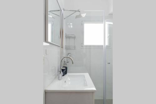 La salle de bains blanche est pourvue d'un lavabo et d'une douche. dans l'établissement Botiuqe apartment . 100 meters from the beach, à Tel Aviv