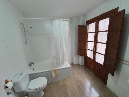 La salle de bains blanche est pourvue de toilettes et d'une baignoire. dans l'établissement Apartamento Balcones del Tajo, à Ronda
