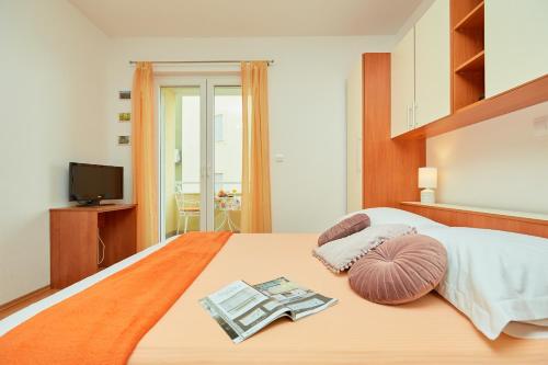 a bedroom with a bed with a book and a tv at Apartments Zelic Tucepi in Tučepi