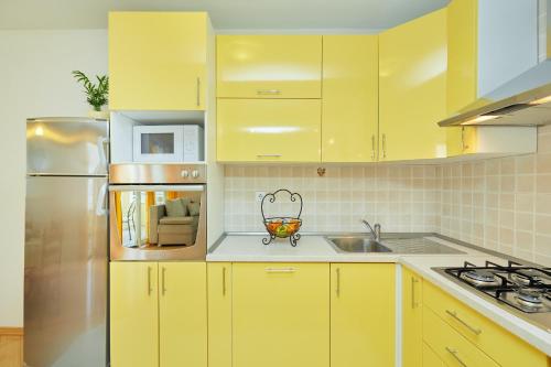 a kitchen with yellow cabinets and a stainless steel refrigerator at Apartments Zelic Tucepi in Tučepi