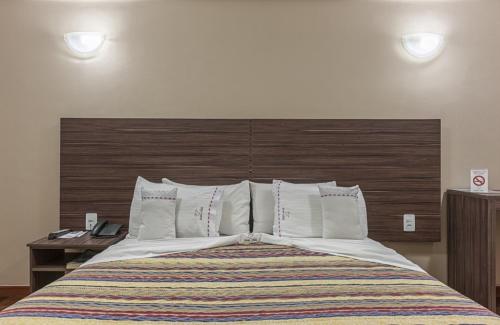 a bedroom with a large bed with a wooden headboard at Abba Hotel in Betim