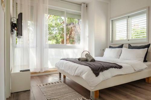 um quarto com uma cama grande, paredes brancas e janelas. em Gordon beach! 2 bedrooms great location em Tel Aviv
