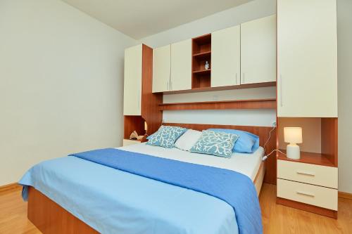 a bedroom with a bed with blue sheets and white cabinets at Apartments Zelic Tucepi in Tučepi
