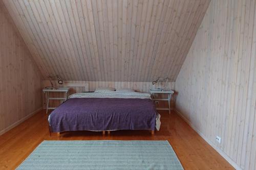 a bedroom with a bed with two tables and two rugs at Captain Alexandri Cottage by the Sea in Kõiguste